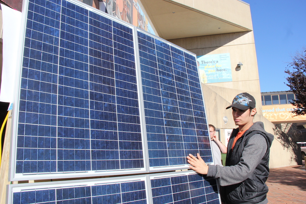 Male student standing beside solar panel